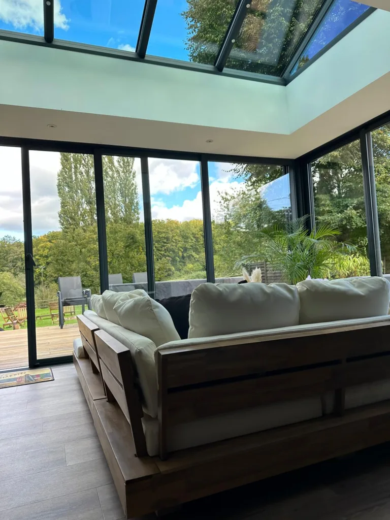 extension normandie faite par concept alu vue de l'intérieur. L'extension est un salon lumineux avec un gros canapé